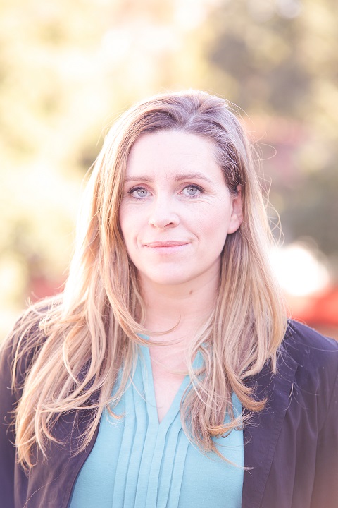 Liz Harmer smiles at the viewer in front of a background of trees.