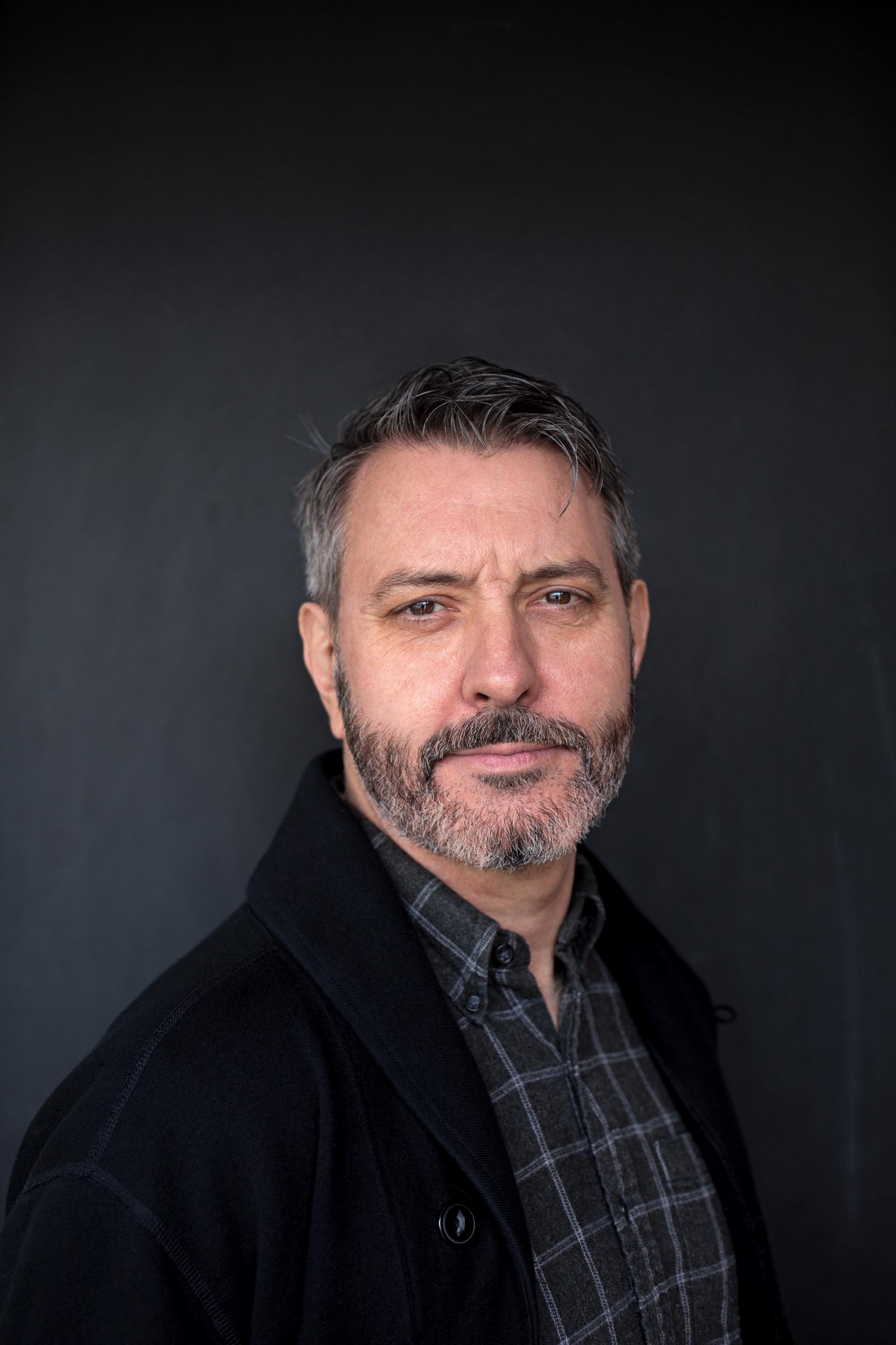 head and shoulders portrait of man with beard wearing a cardigan