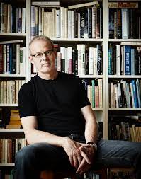 Don Gillmor poses sitting in front of a bookshelf.