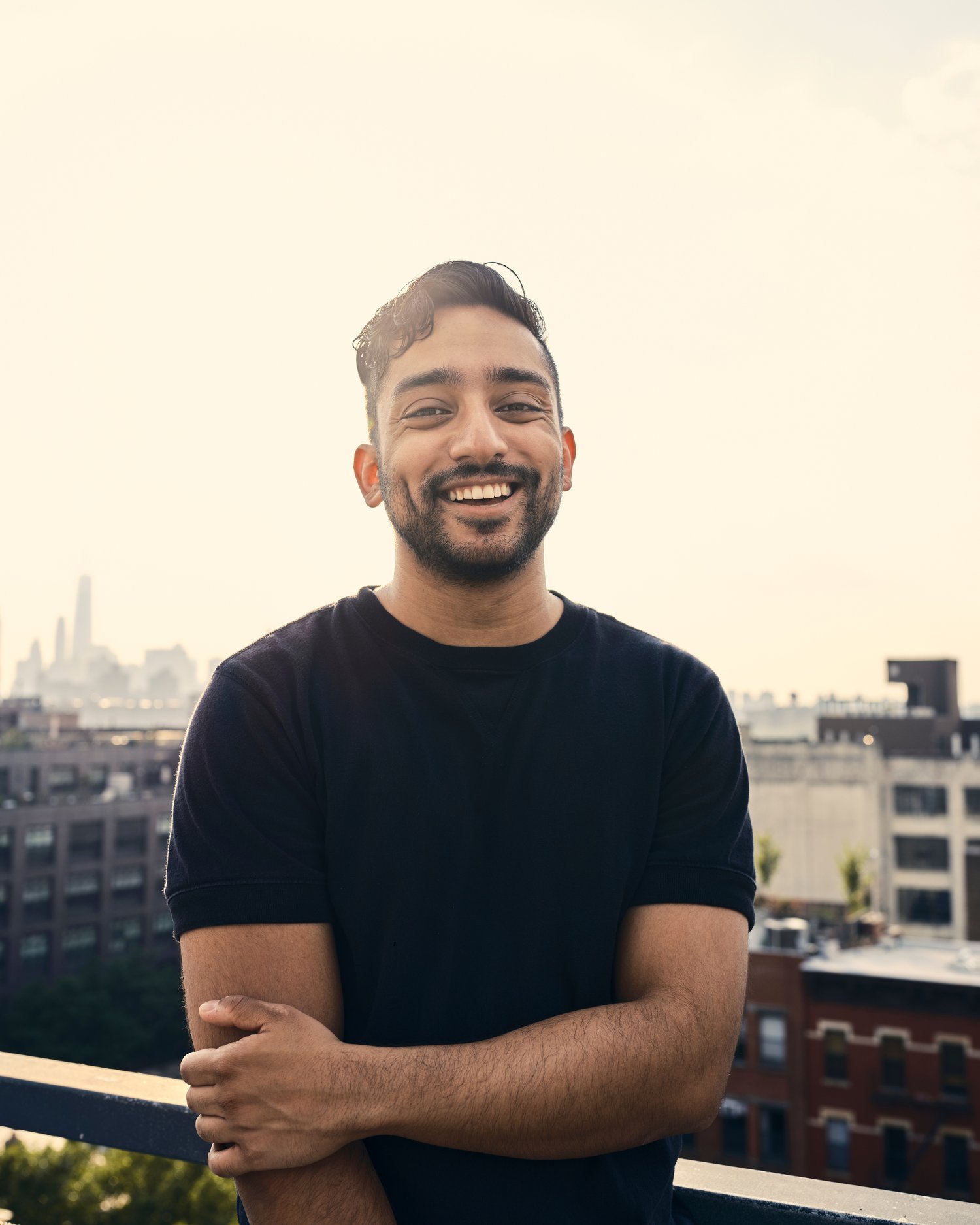 Mayukh smiles at the camera in front of a city backdrop