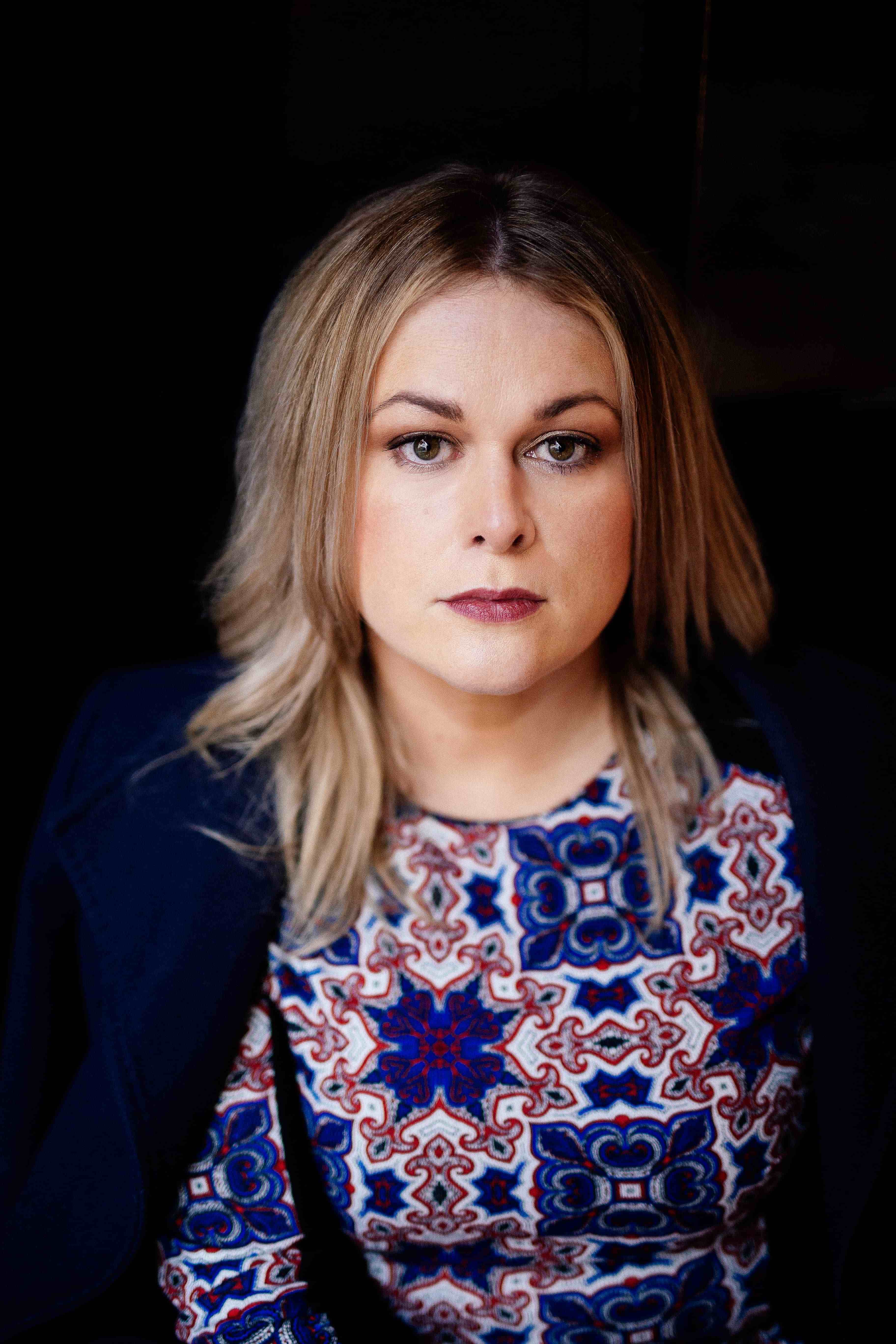 A portrait of author Elaine Feeney against a black background