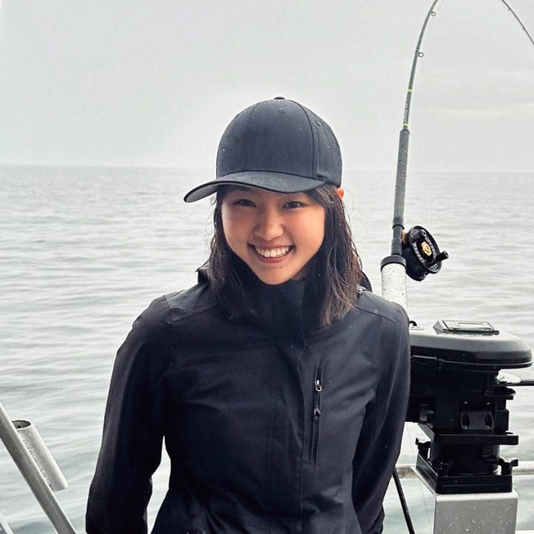 Photo of a young woman in a black hat in front of the ocean