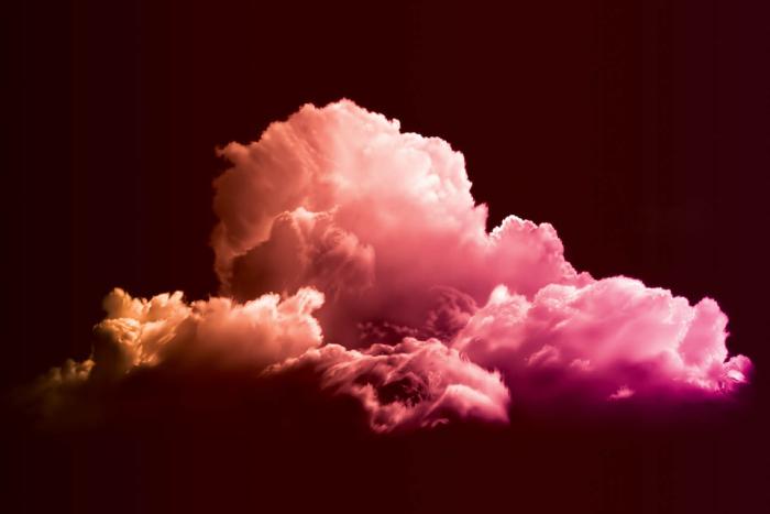 An image of a pink and orange-tinted cloud on a black background. 